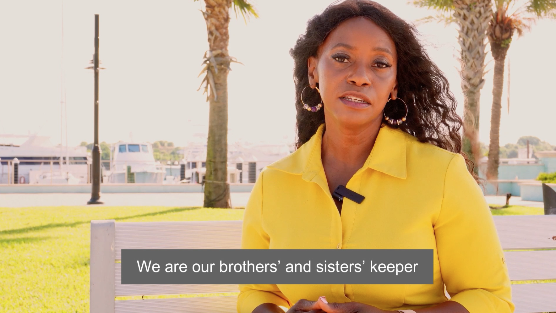 Seated Black woman in yellow dress, with flowing hair and subtitle.